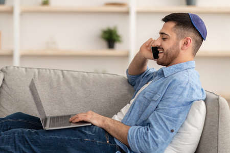 Man working on pc and talking on cellphone at home