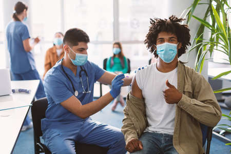 Black Guy Receiving Coronavirus Vaccine Injection In Clinicの写真素材