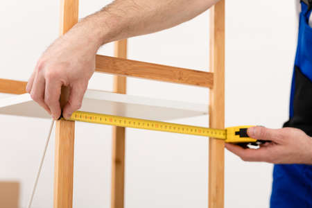 Cropped Shot Of Carpenter Measuring Wooden Shelf With Tape Indoorsの写真素材