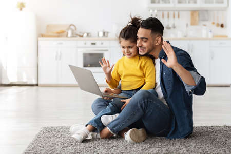 Arab Dad And Little Daughter Making Video Call With Laptop At Home