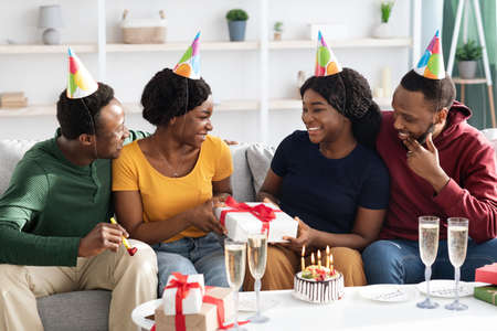 Cute black friends greeting birthday lady at homeの写真素材