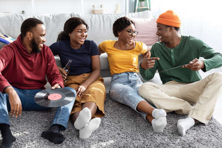 Charismatic black guy showing his friends vynil records