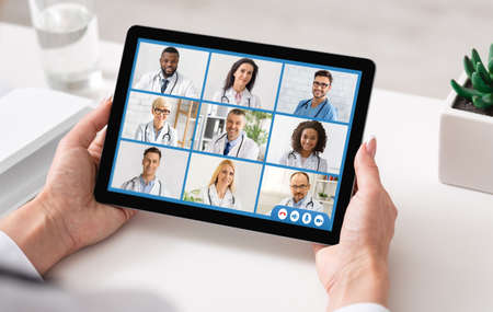 Doctor Lady Making Video Call With Colleagues Using Tablet Indoor