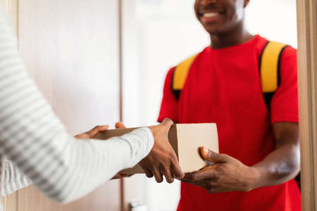 Cropped Shot Of African American Courier Delivering Parcel Indoor