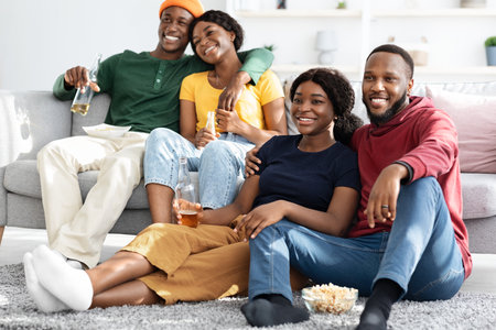 Two loving black couples watching romantic movie at home
