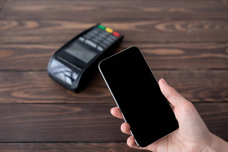 Lady paying contactless from smartphone using modern easy nfc technology, holding cellphone with...