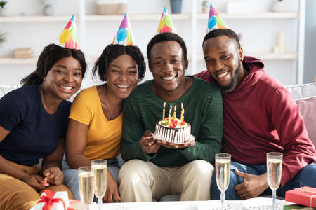 Group of happy black friends having birthday celebration at homeの写真素材