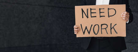 No more money on quarantine concept. Male office worker holding cardboard sign with need work inscriptionの写真素材