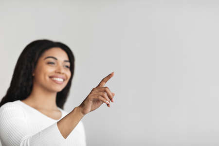 Modern futuristic house control system. Black woman pointing finger in the air pushing button on...