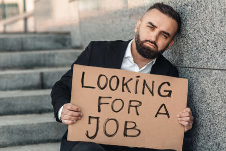 Mature businessman lost his job due to quarantine looking for a job, holding cardboard. Unemployment growth conceptの写真素材