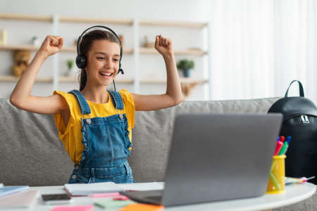 Portrait of emotional girl shaking fists using laptop