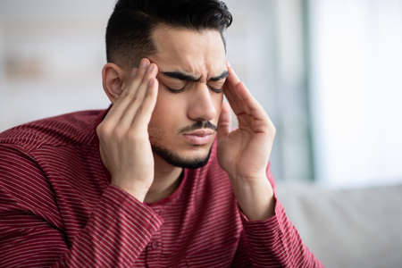 Upset middle-eastern guy suffering from headache, closeupの写真素材