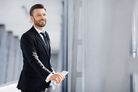 Happy businessman looking through window in airport