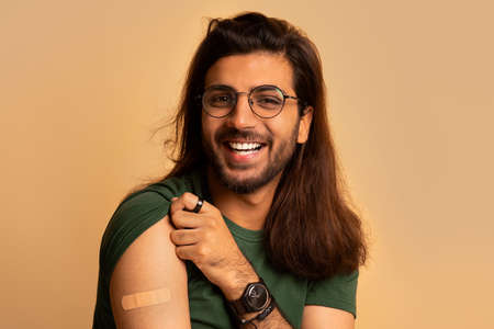 Closeup of happy middle-eastern guy showing shoulder after vaccination