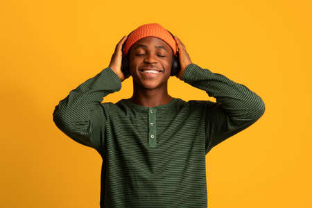 Closeup Portrait Of Happy African American Guy Listening Music In Wireless Headphones