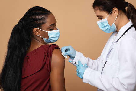 Young nurse making injection for black womanの写真素材