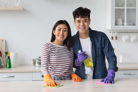 Cheerful asian couple cleaning kitchen at new houseの写真素材