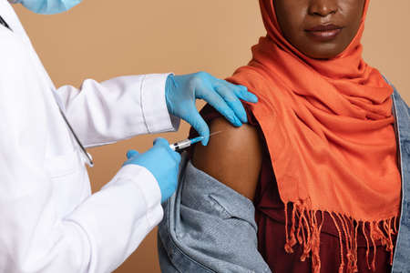 Closeup of nurse hands making injection for muslim black womanの写真素材
