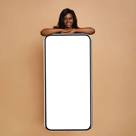 African american lady leaning on huge cellphone with empty screen