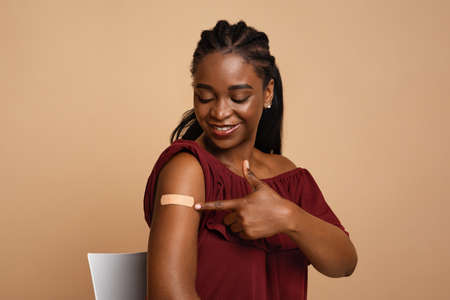 Millennial african american woman pointing at plaster on her armの写真素材