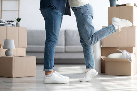 Legs of hugging man and woman standing among moving boxesの写真素材