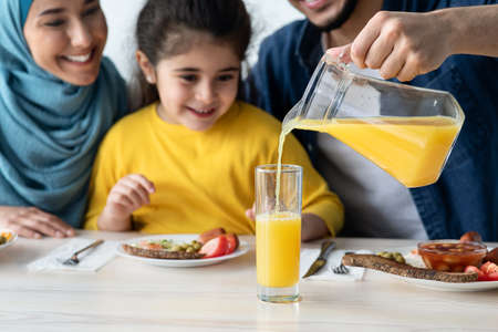 Orange Juice. Caring Man Pouring Healthy Vitamin Drink For Daughter And Wifeの写真素材
