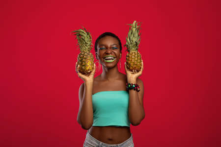 Happy black woman holding two pinapples and laughingの写真素材