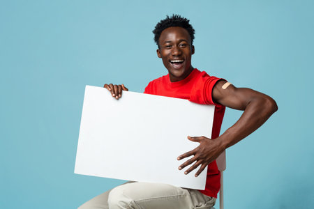 Cheerful Vaccinated Black Guy With Plaster On Arm Holding Blank Placardの写真素材