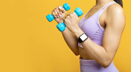Unrecognizable african american lady exercising with two blue dumbbells, wearing fitness tracker with blank screenの写真素材