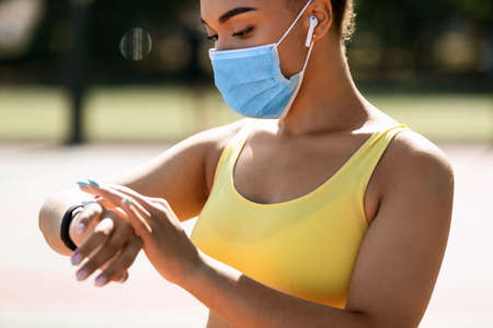 Sporty African woman checking fitness tracker during workout breakの写真素材