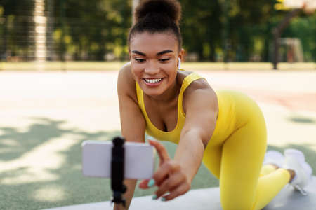 Young black woman recording exercises on smartphone outdoorsの写真素材