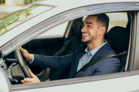 Joyful middle-eastern businessman driving his new auto