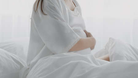 Unrecognizable Pregnant Lady Touching Belly While Sitting In Bed, Suffering Prenatal Contractionsの写真素材