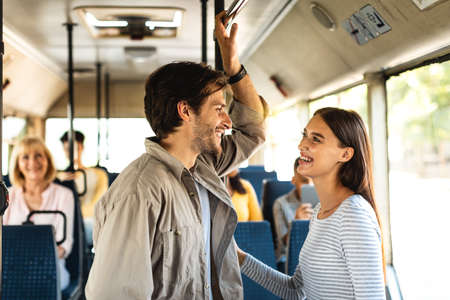 Beautiful smiling couple standing in bus and talkingの写真素材