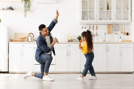 Domestic Concert. Cheerful Arab Dad And Little Daughter Having Fun In Kitchenの写真素材