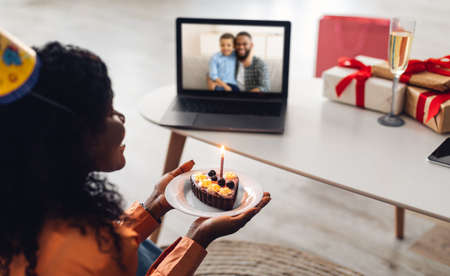 Lady Having Video Call Holding Birthday Cake Near Laptop Indoorの写真素材