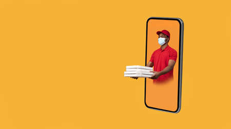 Deliveryman In Cellphone Giving Pizza Boxes To Side, Yellow Backgroundの写真素材