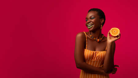 Happy black lady with orange looking at copy spaceの写真素材