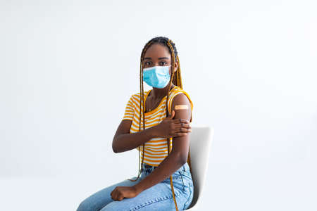 Black woman sitting on chair, showing band on her shoulderの写真素材