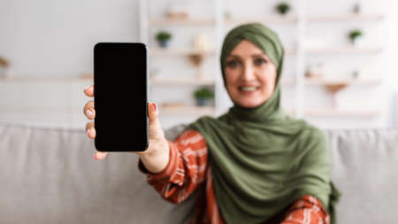 Happy Senior Muslim Woman Showing Smartphone Empty Screen Indoor, Panoramaの写真素材