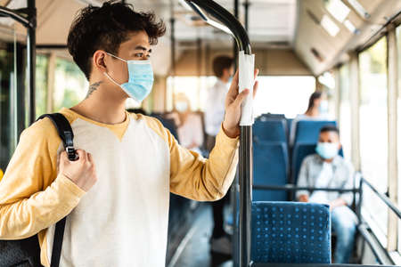 Asian male in face mask standing in bus using tissueの写真素材