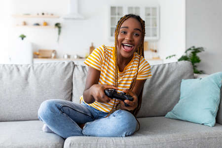Joyful black woman playing video games at homeの写真素材