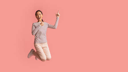 Crazy Sales. Cheerful Excited Asian Female Jumping And Pointing At Copy Spaceの写真素材