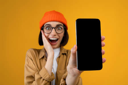 Wow, amazing useful app. Surprised young lady holding smartphone with black blank screen in hand, closeupの写真素材
