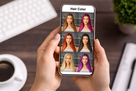 Female hands using hair color simulation app on mobile phone