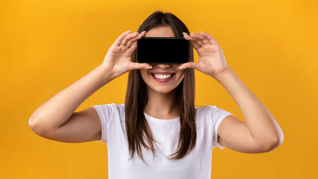 Woman covering eyes with black empty smartphone screen