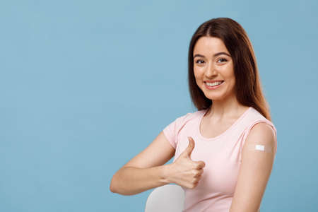 Happy woman showing arm with adhesive plaster and smilingの写真素材