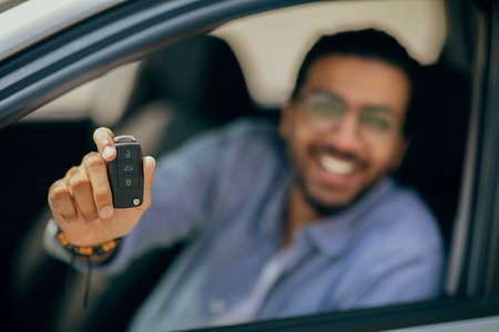 Blurred man showing car key at camera, closeup