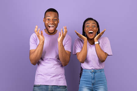 Portrait of excited young black couple hearing great newsの写真素材