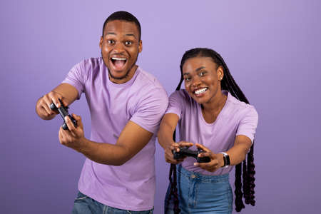 Excited African American couple playing video games together with joysticksの写真素材